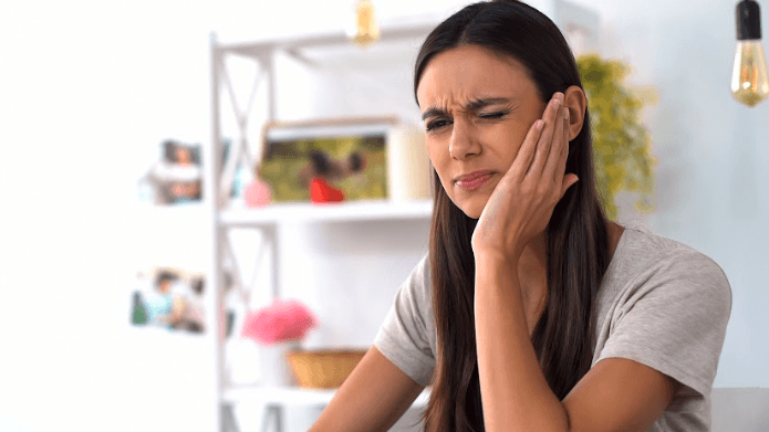 A woman with her hand pressed to her cheek
